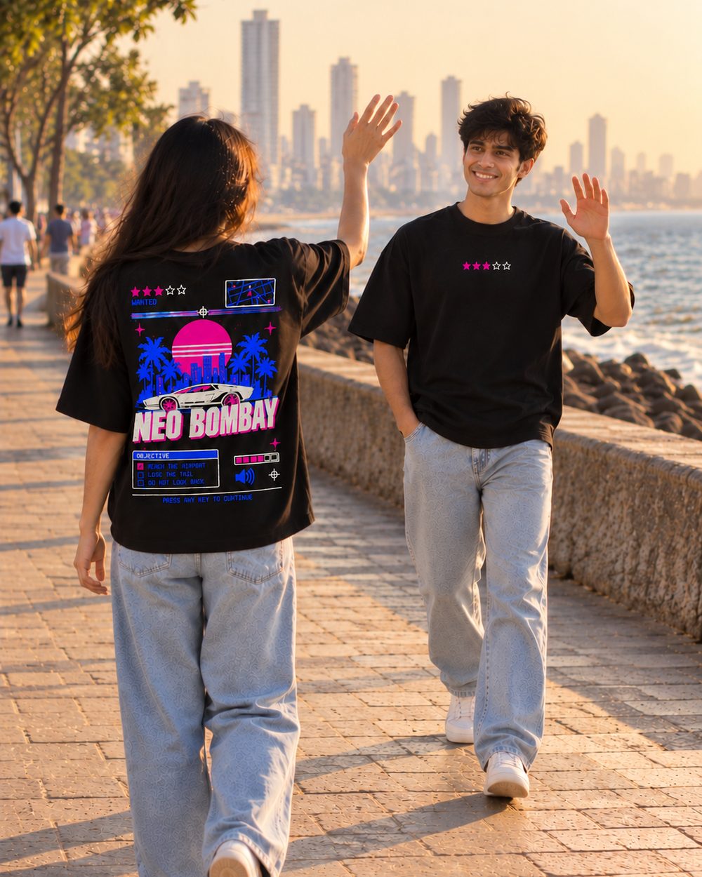 Two people in Neo Bombay tees walking the promenade at sunset, back and chest prints