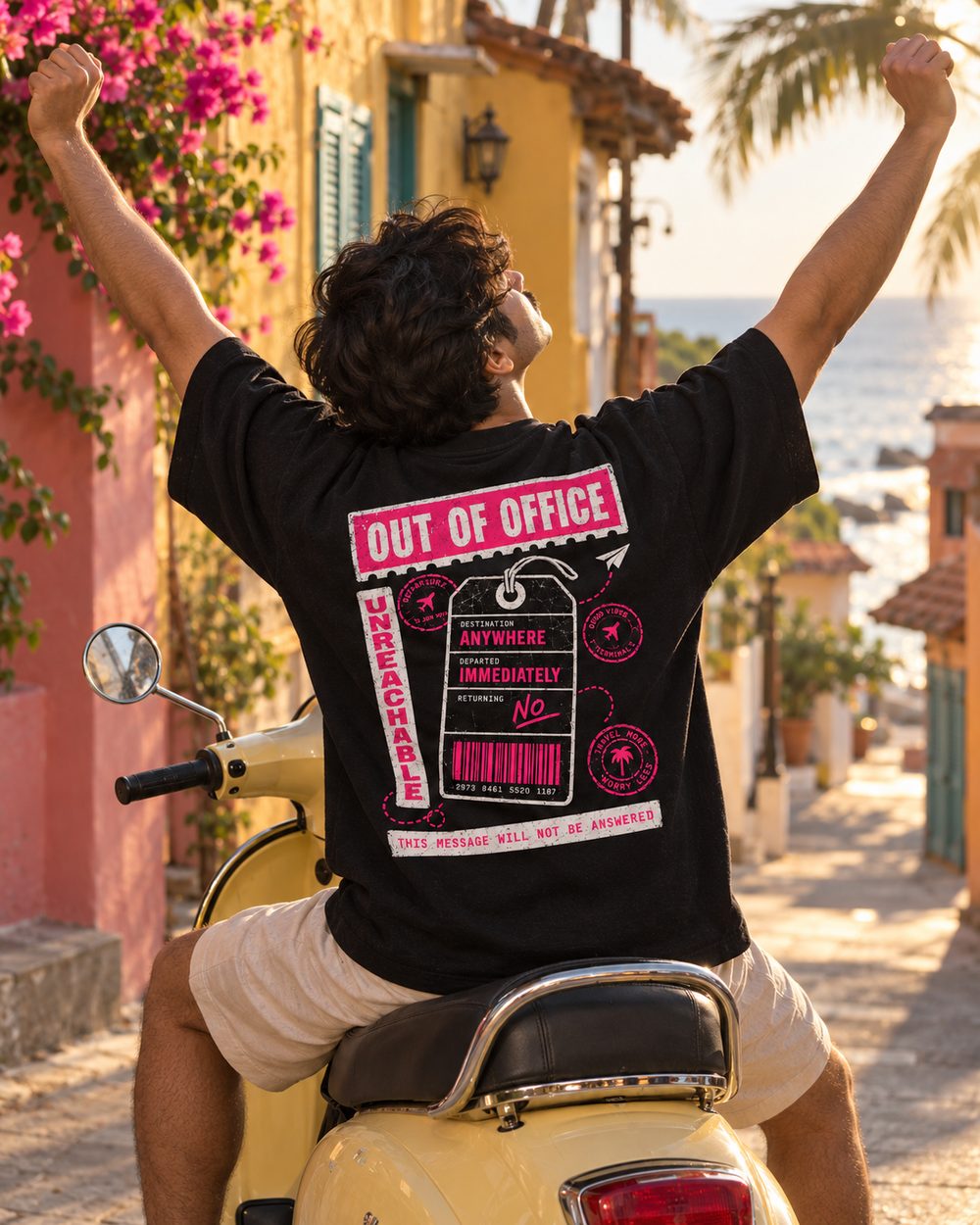 Out of Office tee, luggage tag back print, arm raised on a scooter by the sea