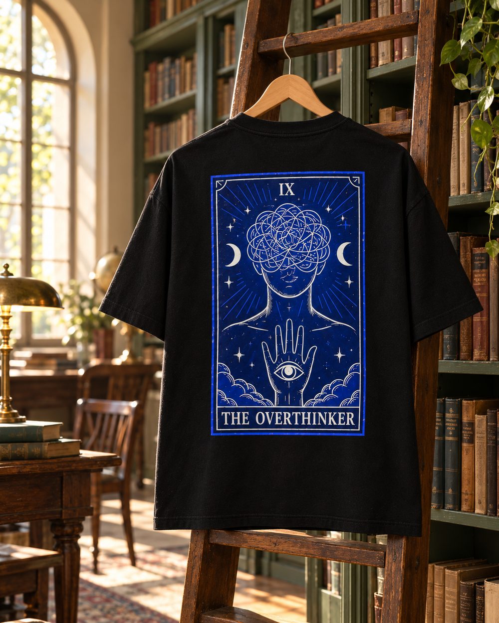 The Overthinker tee on a hanger on a library ladder, tarot card IX back print